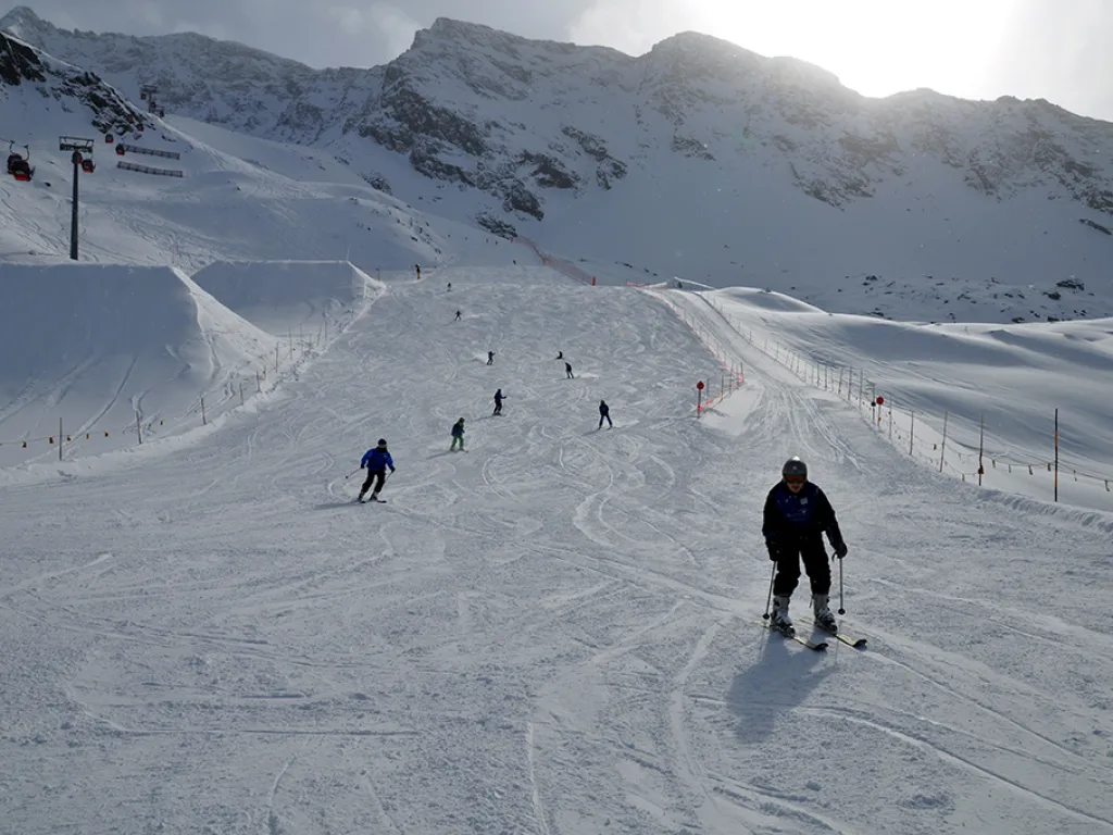 Skifahrer auf der Piste vor der Bergkulisse.